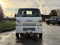 A white 2008 Suzuki Carry van viewed from the front with a simple design featuring a flat windshield and a prominent Suzuki logo on the grille