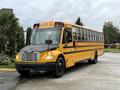 A 2014 Freightliner B2 yellow school bus with a black front and a stop sign displayed on the side