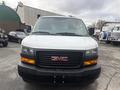 Front view of a white 2022 GMC Savana van with a black grille featuring a prominent red GMC logo