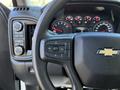 A close-up of the steering wheel and control panel of a 2024 Chevrolet Silverado 1500 featuring a Chevrolet logo and various dashboard gauges