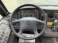 The interior of a 2014 Freightliner B2 featuring a black steering wheel dashboard with various gauges and controls including buttons and switches