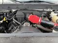 Engine compartment of a 2015 Ford F-350 showcasing various mechanical components including a red intake hose and several hoses and cables