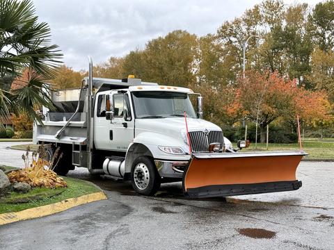 A 2009 International 4400 truck with a large orange snow plow attached to the front and a silver dump bed in the rear