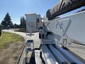A 2013 International 7500 truck equipped with a hydraulic boom lift and bucket extending upward for utility work