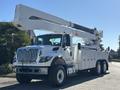 A white 2013 International 7500 bucket truck with an extended boom and storage compartments on the sides