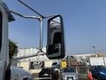 A 2020 Peterbilt 330 truck side mirror mounted on a chrome arm reflecting a parking lot scene