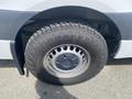 A close-up view of the tire and wheel of a 2025 Mercedes-Benz Sprinter showing a rugged off-road tire design and a metal wheel rim