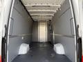 A spacious empty cargo area of a 2023 Mercedes-Benz Sprinter with gray walls and a flat floor designed for transporting goods