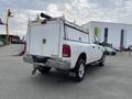 A white 2015 RAM 2500 truck with a utility bed and ladder rack is parked, showcasing its rear and side profiles