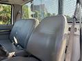 A 2004 Ford F-750 with two gray vinyl seats visible in the foreground and seatbelts attached to each seat