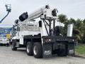 A 2013 Freightliner 114SD truck with a hydraulic lift system mounted on the back and a white exterior