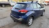 A 2019 Nissan Kicks in blue with a roof rack visible from a rear angle showcasing its compact design and distinctive taillights