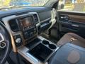 Interior of a 2015 RAM 1500 featuring a touchscreen display center console and leather-trimmed seats with cup holders and controls on the dashboard