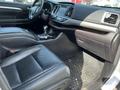 Interior of a 2018 Toyota Highlander featuring black leather seats a central console and a dashboard with various controls and displays