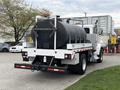 A 2016 Peterbilt 348 truck with a large black tank on the back and silver side panels with reflective tape visible