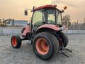 A red and black 2010 Kubota M6040 tractor with large rear tires and a cabin equipped with a steering wheel and control panel