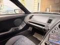 A black interior of a 1997 Toyota Supra featuring a dashboard with control buttons and a modern audio system with a circular dial and display screen