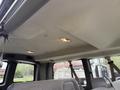 Interior view of a 2004 Chevrolet Express showing the ceiling and overhead lights with gray upholstery and seatbelt straps visible