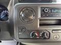 The dashboard controls of a 2021 Ford Econoline featuring air conditioning knobs a radio display and a speedometer