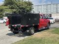 A red 2013 RAM 2500 truck with a black utility bed and toolboxes in the back parked on a gravel surface