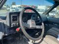 Interior view of a 1996 GMC Top Kick featuring a black steering wheel dashboard with gauges and controls along with a patterned seat
