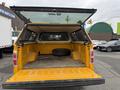 A yellow 2014 Ford F-150 truck bed with a spare tire inside and a cap on the back