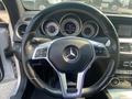 Interior view of a 2013 Mercedes-Benz C-Class steering wheel featuring a multi-functional control panel and three round gauges behind the wheel