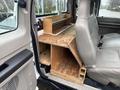 A wooden storage unit built into the rear seat area of a 2008 Ford F-250 SD featuring multiple compartments and a flat surface for tools or equipment