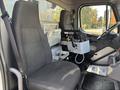Interior view of a 2013 Freightliner 114SD showing two gray seats and a central control console with various knobs and levers