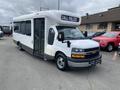 A 2020 Chevrolet Express bus with a white exterior and a sign that reads CALL POLICE on the front window parked with its doors open