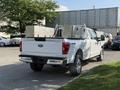 A white 2021 Ford F-150 pickup truck with silver toolboxes in the bed and chrome accents on the rear bumper