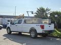 A white 2021 Ford F-150 pickup truck with a chrome tool box in the truck bed and four-wheel drive badge on the side