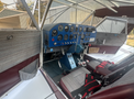 Interior view of a 1986 Sorrell Hiperbipe SNS-7 aircraft featuring a blue instrument panel with various gauges and dials two seats with red harnesses are visible