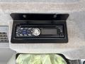 A black car stereo system mounted on a gray surface featuring buttons and a display panel with a silver dial