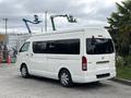 A white 2009 Toyota Hiace van with large windows and a rear sliding door parked, featuring a sleek design and alloy wheels