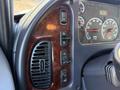 Dashboard controls of a 2011 Freightliner M2 106 featuring buttons for various functions and a vent with a wood grain pattern