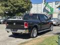 A black 2015 RAM 1500 pickup truck with chrome accents and a crew cab parked at an angle showcasing its rear and side design