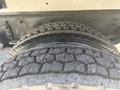 Close-up of a large truck tire showing deep tread patterns and a metal rim, part of a 2022 Freightliner M2 106