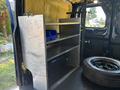 A metal shelving unit with three shelves inside a 2016 Ford Transit 150 van