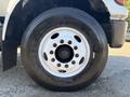 Close-up of a wheel from a 2004 Ford F-750 featuring a white rim with several bolt holes and a large black tire
