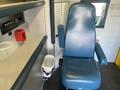 A 2011 Chevrolet Express interior featuring a blue driver's seat with armrests a small waste bin and control panel with various buttons and a digital display