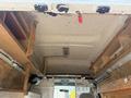 Interior view of a 2008 Ford Econoline van featuring wooden shelves and a ceiling light with structural supports visible