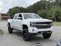 A 2017 Chevrolet Silverado 1500 in white with black accents and off-road tires parked in a lot