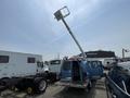 A blue 2005 Ford Econoline van with a raised bucket lift attached to the roof