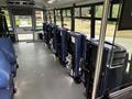 Interior of a 2020 Chevrolet Express showing blue seats and several stowed wheelchair lifts along one side