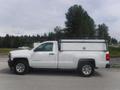 A white 2015 Chevrolet Silverado 1500 pickup truck with a truck bed cover and a ladder rack on the top
