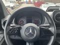 Steering wheel of a 2025 Mercedes-Benz Sprinter featuring controls for audio and cruise settings and the Mercedes-Benz logo in the center