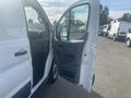 A white 2017 Ford Transit van with its driver's side door open showing the interior and dashboard