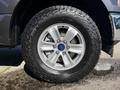 A silver wheel of a 2018 Ford F-150 featuring five spokes and off-road tire tread