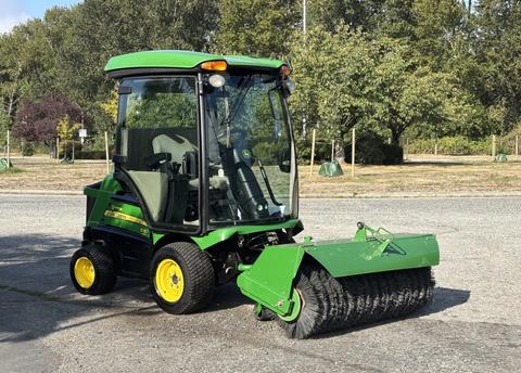 A 2021 John Deere 1575 tractor with a cab and a front-mounted broom attachment for sweeping surfaces